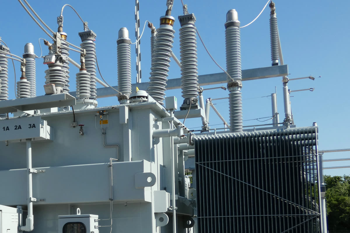 Outdoor power transformer with high and low voltage bushings, surge arresters and a radiator bank against a blue sky
